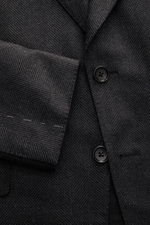 Tom Ford Sakko 'Shelton' dunkelgrau meliert, Slim Fit, taillierter Zwei-Knopf-Stil, tonaler Fischgrat, weicher Griff, Detailaufnahme von Vorderseite mit Ärmel.