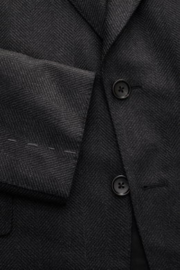 Tom Ford Sakko 'Shelton' dunkelgrau meliert, Slim Fit, taillierter Zwei-Knopf-Stil, tonaler Fischgrat, weicher Griff, Detailaufnahme von Vorderseite mit Ärmel.