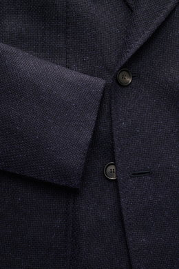 Nahaufnahme des Stile Latino Sakko 'Andrea' dark navy von vorne schräg oben, zeigt Panama-Stoff aus Wolle, Alpaka und Seide, Zweireiher mit Spitzrevers, weicher Griff, Slim Fit, drei Knöpfe, klassische Brusttasche, aufgesetzte Hüfttaschen, unfertige Ärmel