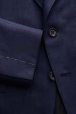 Nahaufnahme des Tom Ford Sakkos 'Shelton' navy mit Fischgratmuster, zwei Knöpfen, Spitzrevers und unfertigen Ärmeln aus Woll-Mix.