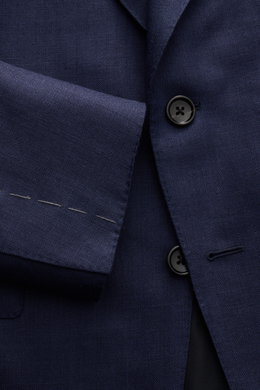 Nahaufnahme des Tom Ford Sakkos 'Shelton' navy mit Fischgratmuster, zwei Knöpfen, Spitzrevers und unfertigen Ärmeln aus Woll-Mix.