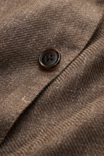 Nahaufnahme eines Knopfs und der materialtypischen Struktur des graubraunen melierten Belvest Sakkos aus Leinen und Wolle.