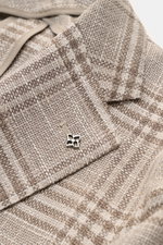 Nahaufnahme des fallenden Revers mit markentypischem Pin des Tagliatore Sakko 'Monte Carlo' beige/taupe kariert aus Unconstructed-Materialmix.