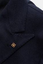 Nahaufnahme des spitz zulaufenden Revers vom Tagliatore Seidensakko 'Vesuvio' navy aus reiner Seide mit weichem Griff und markant strukturierter Webung, goldfarbener Pin am Revers sichtbar.