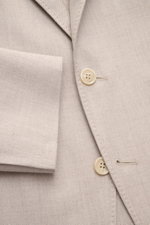 Brunello Cucinelli Sakko sand meliert, Nahaufnahme von Knöpfen, fallendem Revers, tailliertem Drei-Knopf-Stil, weichem Cashmere-Seide-Mix, markanter Webstruktur.