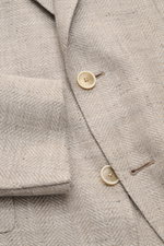 Nahaufnahme aus schräger Perspektive des Caruso Sakkos 'Aida' beige meliert mit Fischgratstruktur, Leinen-Woll-Mix, Slim Fit, Zwei-Knopf-Stil und halbfertigen Ärmeln.