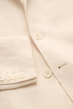 Nahaufnahme des Percival Sakkos 'Tailored Linen' creme aus atmungsaktivem Leinen-Baumwoll-Mix mit Knöpfen am Ärmel und fallendem Revers.