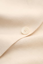 Nahaufnahme des cremefarbenen Percival Sakko "Tailored Linen" mit feiner Leinen-Baumwoll-Struktur und Knopf an Ärmelabschluss.