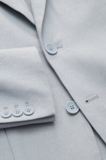 Nahaufnahme des Percival Sakkos 'Tailored Linen' rauchblau aus atmungsaktivem Leinen-Baumwoll-Mix, zeigt Knöpfe, Ärmel mit Knopfleiste und fallendes Revers, fotografiert von oben.