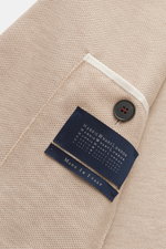 Nahaufnahme des Harris Wharf London Blazer beige, fotografiert von innen mit Fokus auf feine Waffelstruktur, Loro Piana Baumwolle, Button und Etikett.