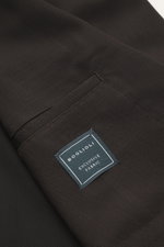 Close-up of the Boglioli Blazer dark brown fabric from a top-down perspective, showing pure new wool, soft touch, fine tonal herringbone, Slim Fit, tailored two-button style, notched lapel, classic breast pocket, patch hip pockets, kissing buttons, rear s