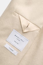 Close-up top-down view of the Boglioli Beige Melange Knit Blazer showcasing its fine silk-cashmere knit texture and label.

Description: <p>Exquisite knit blazer by BOGLIOLI: Crafted from a luxurious silk-cashmere blend with a refined knit texture, this p