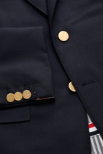 Nahaufnahme von Thom Browne Sakko navy aus reiner Wolle mit goldfarbenen Kissing Buttons, fallendem Revers und Ripsband-Tricolore, Slim Fit.