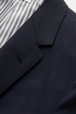 Nahaufnahme des fallenden Revers und gestreiften Innenfutters vom maritim monochromen Thom Browne Sakko navy aus reiner Wolle.
