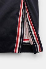 Nahaufnahme der Thom Browne Daunenjacke navy mit Ripsband in Tricolore, Detail der Seitenschlitze und wärmender Daunenfüllung.