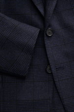 Close-up front angled view of Cesare Attolini Navy/Black Checked Blazer featuring slim fit, tailored three-button style, notched lapel, classic breast pocket, patch hip pockets, unfinished sleeve cuffs, rear side vents, half lined, three inner pockets, so