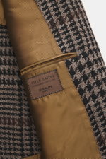 Close-up top view of the Stile Latino Blazer 'Vincenzo' taupe/black checkered showing wool-alpaca blend fabric and golden inner lining with label.

The classic blazer 'Vincenzo' by STILE LATINO imparts a distinctly Italian character: the fabric made of a 