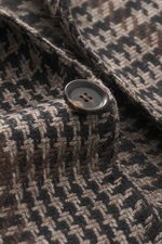 Close-up front angle of the Stile Latino Blazer 'Vincenzo' taupe/black checkered showing a wool-alpaca blend coarse houndstooth weave fabric button. The classic blazer 'Vincenzo' by STILE LATINO imparts a distinctly Italian character: the fabric made of a