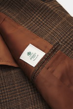 Close-up top-down view of Borrelli Blazer 'Procida' brown/dark brown checkered showing mix of wool and silk, slightly textured feel, classic Glencheck, slim fit, tailored three-button style, notched lapel, classic breast pocket, patch hip pockets, unfinis