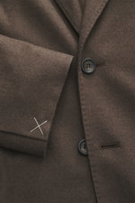 Close-up front view of Colombo Kid Cashmere Blazer 'Robert' taupe, showcasing soft kid cashmere, notched lapel, tailored two-button style, classic breast pocket, patch hip pockets, unfinished sleeve cuffs with white stitching, and branded button.
