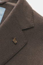 Nahaufnahme des taupefarbenen Colombo Kid Cashmere Sakko 'Robert' aus reiner, sehr weicher Kid Cashmere-Qualität, fotografiert schräg von oben mit sichtbarem fallendem Revers und dekorativem Ansteck-Accessoire, Unconstructed Design mit Slim Fit, zwei Knöp