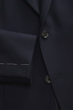 Close-up front view of Lardini Jersey Blazer navy showing slim fit, elastic virgin wool jersey, soft touch, tailored two-button style, notched lapel with flower pin, classic breast pocket, patch hip pockets, unfinished sleeve ends, rear side vents, uncons