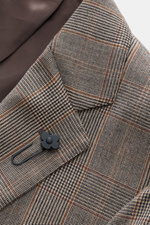 Nahaufnahme des fallenden Revers mit Blüten-Anstecker des Lardini Sakko beige/schwarz kariert, Glencheck-Muster, reine Schurwolle, Slim Fit, Unconstructed Design, von oben fotografiert.