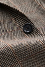 Close-up image from above of the Lardini Blazer Beige/Black Checked showing pure virgin wool fabric with soft touch, Glencheck woven pattern, slim fit, tailored two-button style, notched lapel with flower pin, classic breast pocket, patch hip pockets, unf