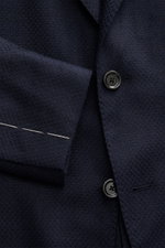 Close-up front view of Lardini Navy Blazer showing textured navy fabric, black buttons, and white stitching; mix of cashmere and silk, airy Panama weave, soft touch, Slim Fit, dropped lapel with flower pin, tailored two-button style, classic breast pocket