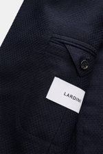 Close-up front angle of Lardini Navy Blazer in airy Panama weave, mix of cashmere and silk, soft touch, Slim Fit, dropped lapel with flower pin, tailored two-button style, classic breast pocket, patch hip pockets, unfinished sleeve cuffs, rear side vents,