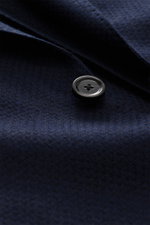 Close-up front view of the Lardini Navy Blazer fabric and button, featuring a mix of cashmere and silk, airy Panama weave, soft touch, slim fit, dropped lapel with flower pin, tailored two-button style, classic breast pocket, patch hip pockets, unfinished