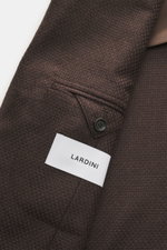Close-up front-side view of the Lardini Blazer dark brown showing slim fit, mix of cashmere and silk, airy Panama weave, soft touch, dropped lapel with flower pin, tailored two-button style, classic breast pocket, patch hip pockets, unfinished sleeve cuff