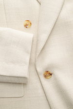 Close-up front view of the Lardini Blazer sand melange showing double-breasted two-button style, notched lapel with flower pin, classic breast pocket, patch hip pockets, mix of virgin wool and silk, structured jersey, soft touch, lightweight quality, slim