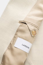 Close-up view of the Lardini Blazer sand melange showing the mix of virgin wool and silk, structured jersey, soft touch, lightweight quality, slim fit, double-breasted two-button style, notched lapel with flower pin, classic breast pocket, patch hip pocke