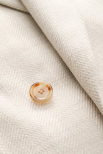 Close-up front view of Lardini Blazer sand melange showing textured fabric with a tortoiseshell button, mix of virgin wool and silk, structured jersey, soft touch, lightweight quality, slim fit, double-breasted two-button style, notched lapel with flower 