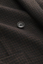 Close-up view of the Tagliatore Blazer dark brown/black checkered fabric showing a button and subtle houndstooth pattern, highlighting its virgin wool-silk blend and soft touch.