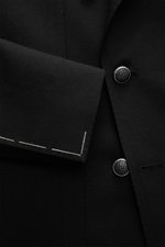 Close-up view of the Tagliatore Black Blazer’s black pure new wool fabric, showing detailed buttons, sleeve cuff, and textured weave.

Description: <p>The double-breasted blazer by TAGLIATORE made of pure new wool combines Italian tailoring craftsmanship 