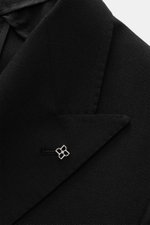 Close-up front-left view of the Tagliatore Black Blazer's peak lapel and silver pin, showing its textured pure new wool fabric.

Description: 
<p>The double-breasted blazer by TAGLIATORE made of pure new wool combines Italian tailoring craftsmanship with 