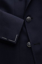 Close-up front view of the Tagliatore Blazer navy showing the textured pure virgin wool fabric, double-breasted three-button style with distinctive buttons, peak lapels, and unfinished sleeve ends. The blazer combines Italian tailoring with contemporary l