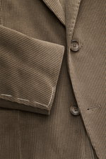 Close-up front view of Tagliatore Cord Blazer taupe in soft cotton-wool corduroy, slim fit with two buttons, notched lapel, classic breast pocket, patch hip pockets, unfinished sleeve cuffs, rear vents, unconstructed design, and brand pin.