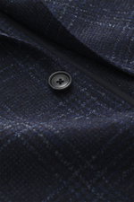 Close-up front view of the Tagliatore Blazer navy/black checked showing virgin wool and microfiber fabric, soft feel, Prince of Wales pattern, slim fit, tailored two-button style, notched lapel with brand pin, classic breast pocket, patch hip pockets, rea