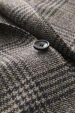 Close-up front view of Tagliatore Blazer grey/black checked showing button detail and fabric texture, mix of virgin wool and cashmere, soft touch, Prince of Wales pattern, slim fit, tailored two-button style, notched lapel with brand-typical pin, classic 