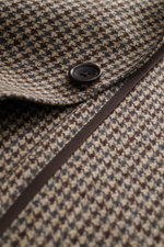 Close-up angled view of Tagliatore Blazer beige/dark brown/navy patterned fabric showing a black button and fine textured pure virgin wool with timeless houndstooth pattern, soft touch, slim fit, tailored two-button style, notched lapel with brand pin, cl