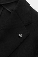 Close-up top view of the Tagliatore Black Blazer's notched lapel, showcasing wool-cashmere fabric, slim fit, and signature pin.

Description: <p>The unconstructed processing made from fine wool with cashmere makes this blazer by TAGLIATORE an exclusive co