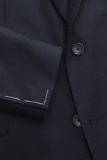 Close-up front view of Tagliatore Navy Blazer showing wool with cashmere content, soft touch, slim fit, tailored two-button style with notched lapel, brand-typical pin on lapel, classic breast pocket, patch hip pockets, unfinished sleeve cuffs, back side 