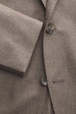 Close-up frontal view of the Tagliatore Blazer taupe showing wool with cashmere content, soft touch, slim fit, tailored two-button style, notched lapel with brand-typical pin, classic breast pocket, patch hip pockets, unfinished sleeve cuffs, back side ve