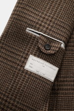 Close-up angled view of Brunello Cucinelli Blazer navy/black checkered showing classic breast pocket with button, label, and texture. Virgin wool with cashmere content, soft touch, slim fit, tailored three-button style, notched lapel, classic breast pocke