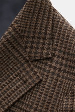 Close-up view of the Brunello Cucinelli Blazer navy/black checkered fabric and sleeve area, featuring virgin wool with cashmere content, soft touch, slim fit, tailored three-button style, notched lapel, classic breast pocket, hip pockets with flap, ticket
