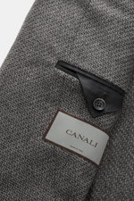 Close-up image from above of the Canali Blazer grey patterned showing pure wool fabric with distinctive woven pattern, soft touch, slim fit, tailored two-button style, notched lapel, classic breast pocket, hip pockets with flap, sleeve ends unfinished, re
