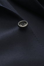 Close-up view of a black button on the navy tonal woven pattern wool with silk Canali Blazer navy, featuring soft touch, slim fit, tailored two-button style, notched lapel, classic breast pocket, hip pockets with flap, unfinished sleeve cuffs, rear side v